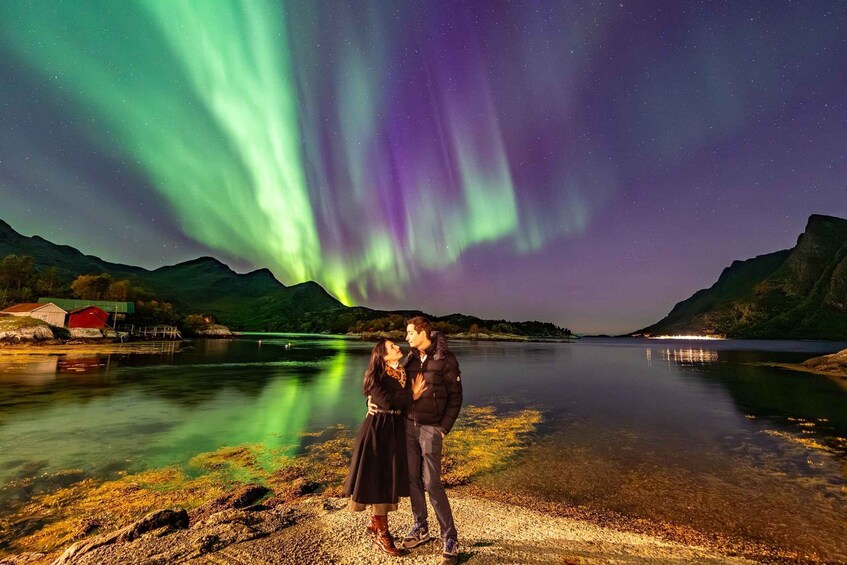A couple standing by a lake with the aurora borealis in the background. 4