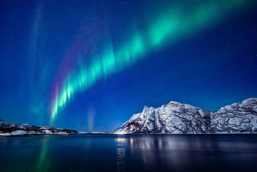 The Northern Lights over a snow-covered mountain and calm lake. 2