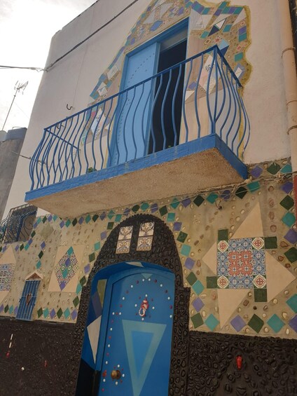 A building with a blue door, a balcony with blue railings, and colorful geometric tile patterns. 3