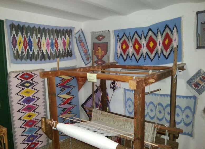 A weaving loom with colorful textiles in the background. 5