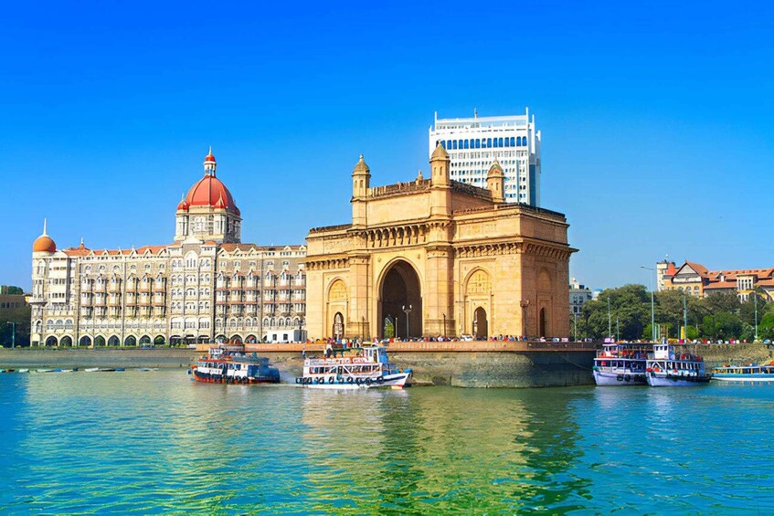 The Gateway of India in Mumbai, with the Taj Mahal Palace Hotel in the background and boats on the water. 4