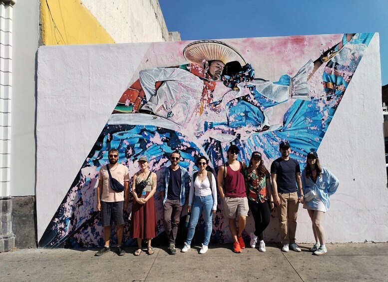 A group of people standing in front of a colorful mural. 1