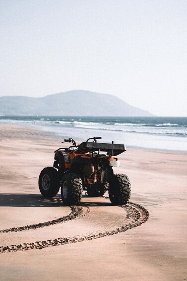 An ATV on a sandy beach with ocean waves in the background. 2