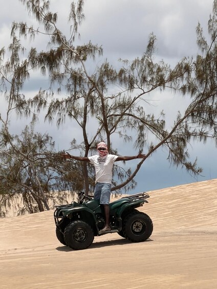 A person on an ATV in a desert with sparse vegetation and a cloudy sky. 5