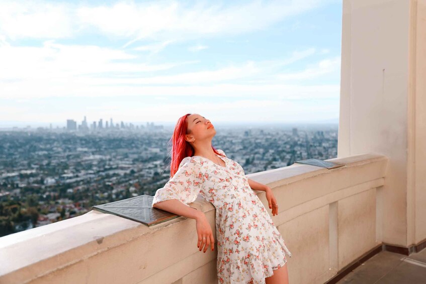 A person leaning on a balcony railing with a cityscape in the background. 1