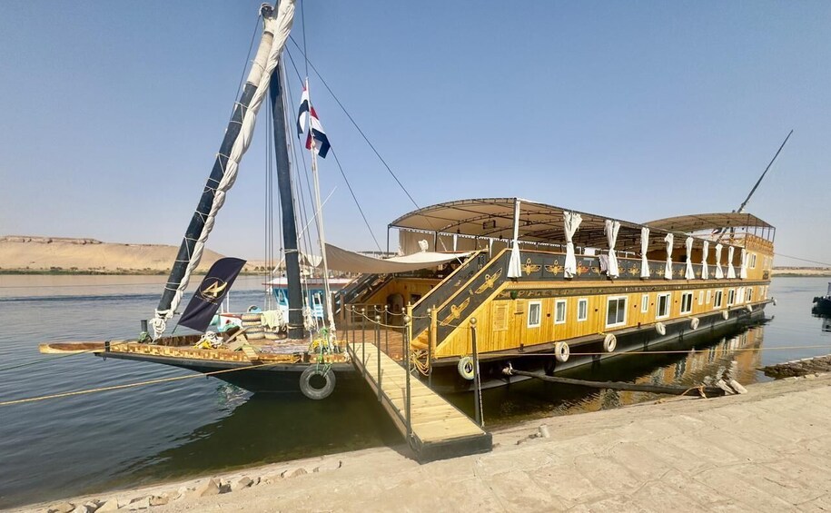 A yellow riverboat docked at a pier with a covered deck and a flag. 2