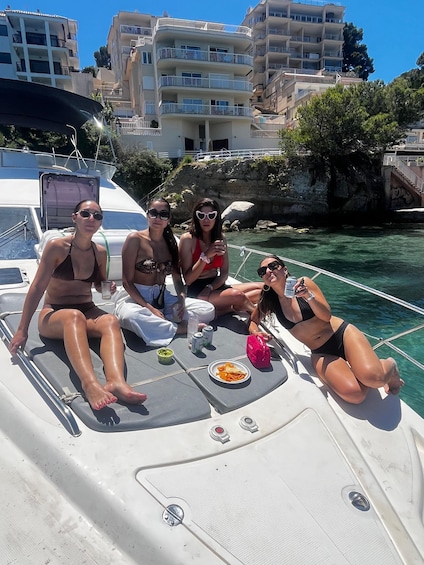 A group of people on a boat with a rocky coastline and buildings in the background. 2