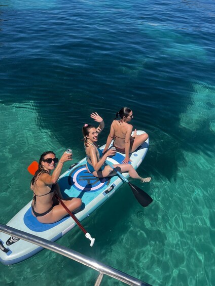Three people on a paddleboard in clear water. 3