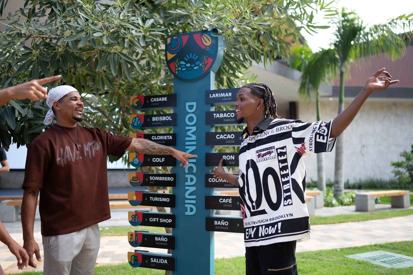 Two people pointing at a signpost with various destinations listed. 1