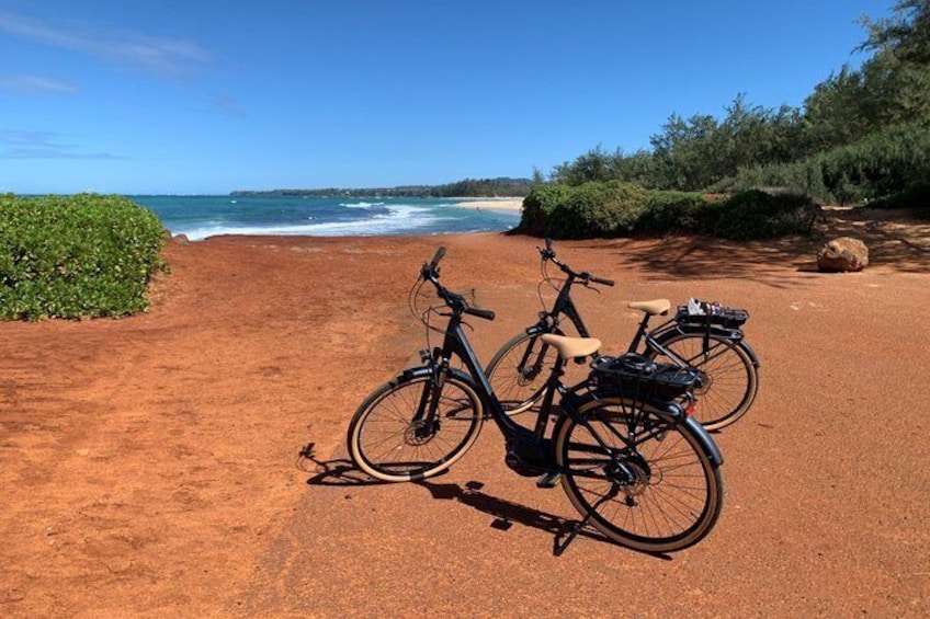 Two bicycles parked on a sandy beach with the ocean in the background. 3