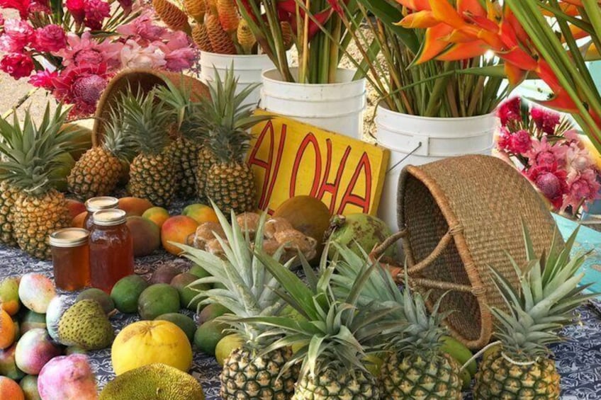 A variety of tropical fruits and flowers, including pineapples, mangoes, and orchids, displayed in white buckets. 5