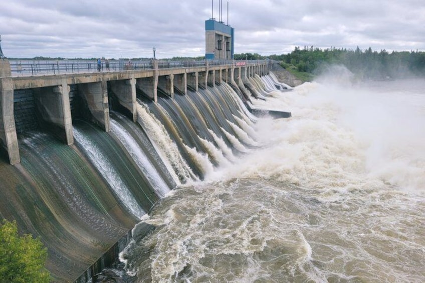 A dam with water cascading down, a bridge, and a tower. 1