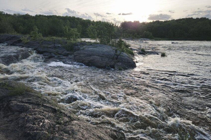 A river with turbulent waters, rocky banks, and a forested area in the background. 2