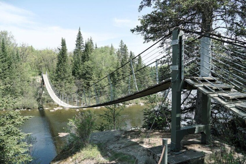 A suspension bridge over a river, surrounded by dense forest. 4