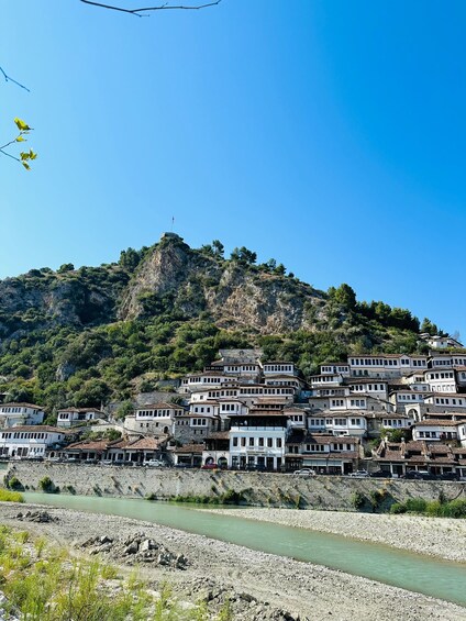 A hillside settlement with buildings, a river, and a flag on a peak. 1