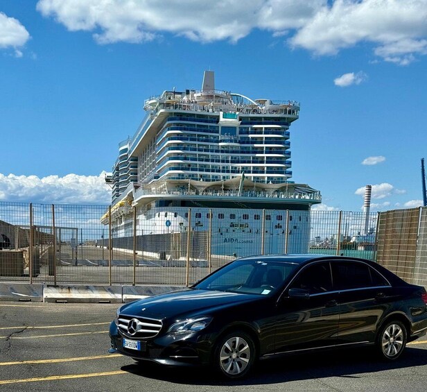 A black Mercedes-Benz parked in front of a large cruise ship under construction. 4