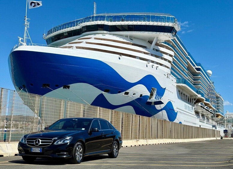A large cruise ship docked at a port with a Mercedes-Benz car parked nearby. 5