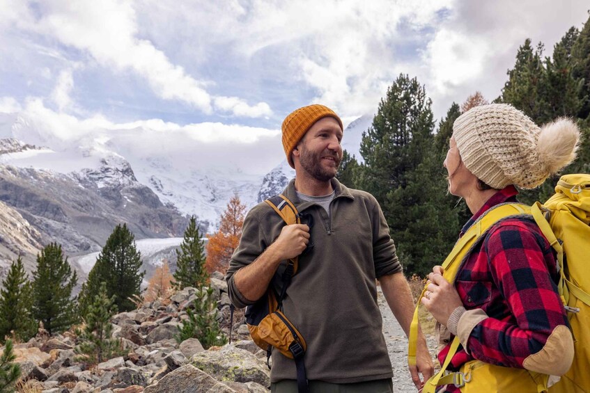 Two hikers in a mountainous area with a glacier in the background. 3
