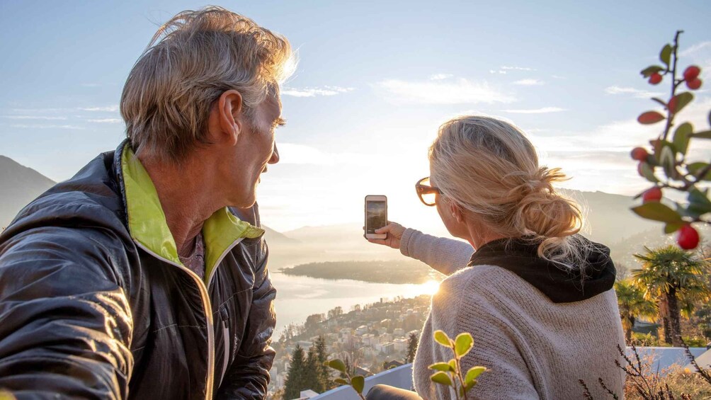 A couple taking a selfie with a scenic view of a town and mountains in the background. 5