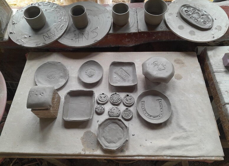 Various pottery items, including cups, plates, and decorative shapes, displayed on a workbench. 1