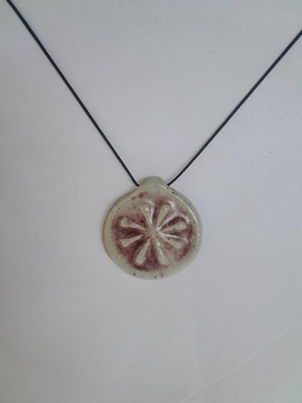 A necklace with a circular pendant featuring a radial pattern. 5