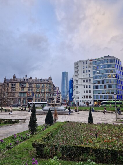 A city square with a fountain, surrounded by historic buildings and modern architecture. 5