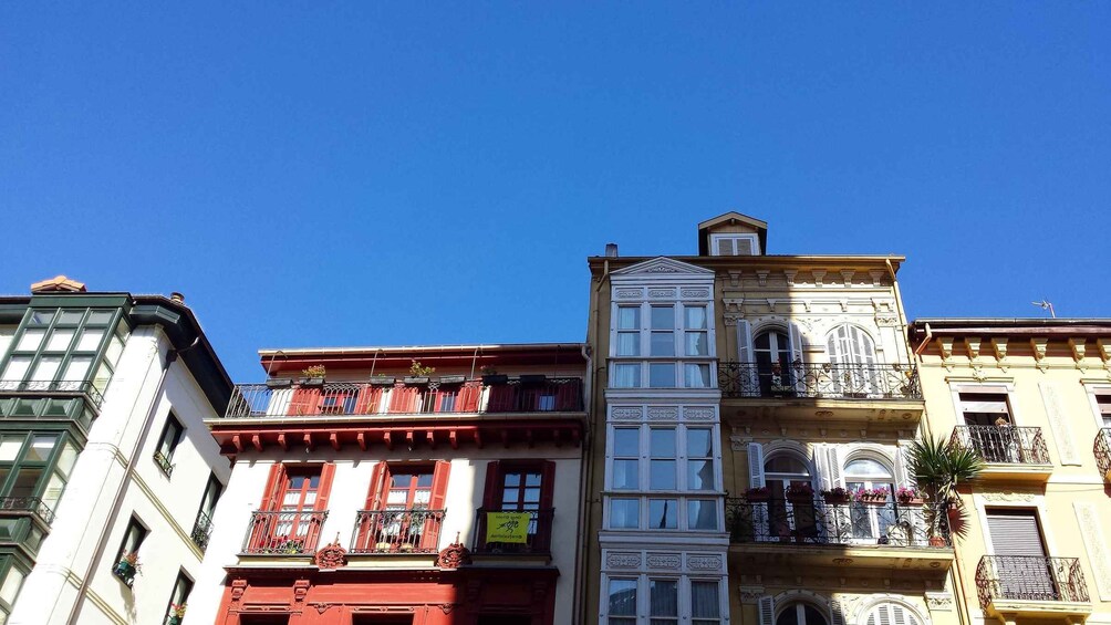 A row of colorful buildings with balconies and shutters, under a clear blue sky. 2
