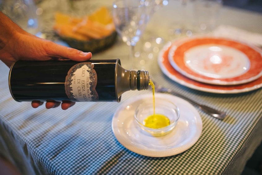 A hand pouring olive oil into a small bowl on a plate. 2