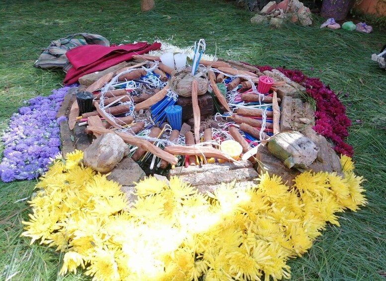 A circular arrangement of flowers and various objects, including ropes and sticks, on a grassy area. 3