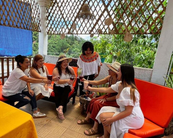 A group of people sitting on orange chairs in an outdoor setting with a wooden lattice structure overhead. 2