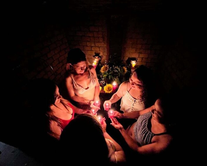 A group of people sitting around a table with candles and flowers, in a dimly lit room with brick walls. 1