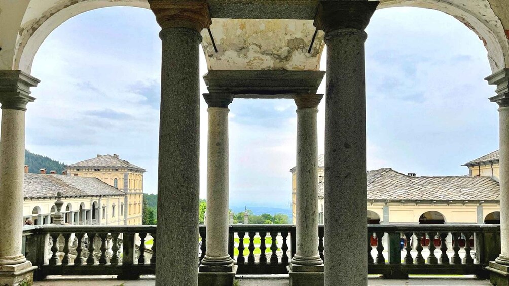 A stone balcony with columns, overlooking a historic building and a distant view of the landscape. 2
