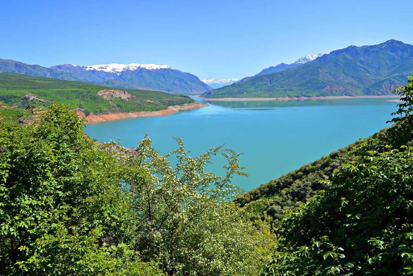 A lake surrounded by mountains with snow-capped peaks in the distance. 5