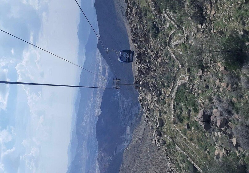 A cable car system in a mountainous area with rocky terrain and sparse vegetation. 1