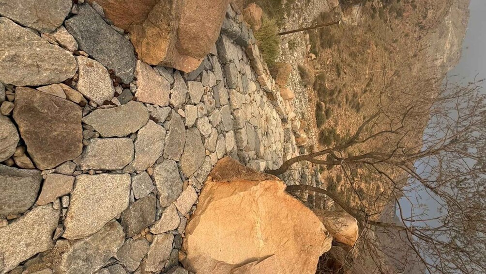 A rocky terrain with a stone wall and a large boulder. 3