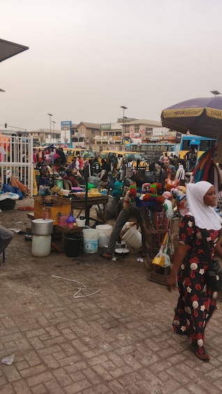 A bustling outdoor market with various stalls selling goods, a bus, and people walking around. 2