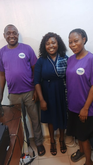 Three people standing in front of a podium with a microphone, wearing purple shirts with 'ADEX TOUR' logos. 4