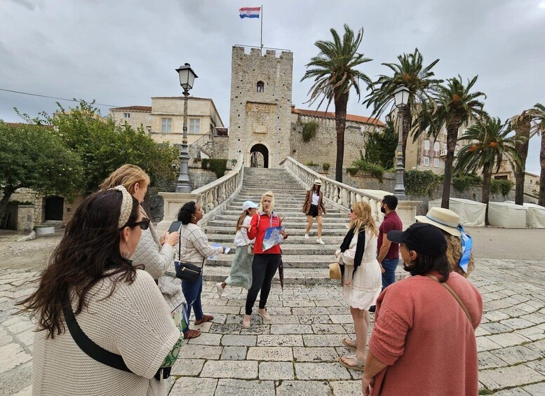A group of people standing on a stone staircase with a castle in the background. 2