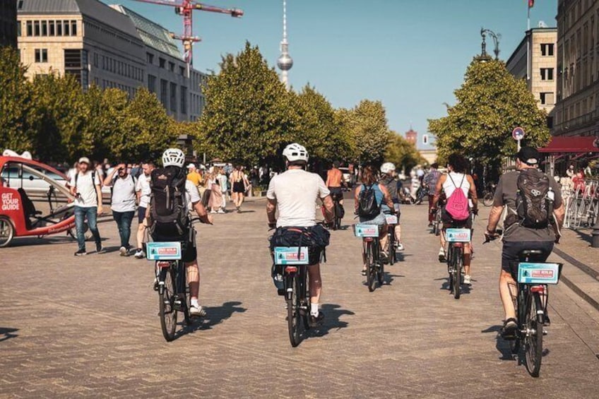 A group of cyclists on a city street with a tower in the background. 2