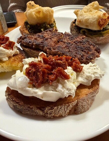 A plate with various food items including a steak, a sandwich with a creamy topping, and a pastry with a golden-brown crust. 1