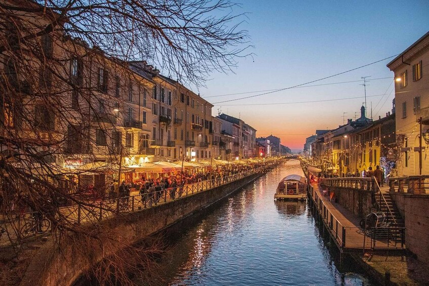 A canal with buildings on either side, a boat, and a bridge. 5