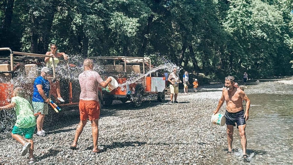 People playing with water near a riverbank, with trees in the background. 3