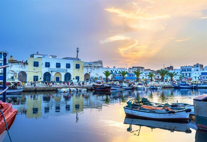 A harbor with boats, a waterfront promenade, and buildings with arches. 1