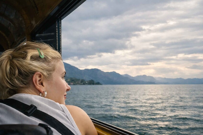A person on a boat with mountains in the background. 3