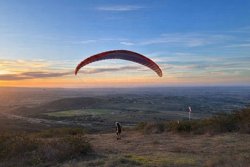 A person paragliding over a landscape with a sunset in the background. 2