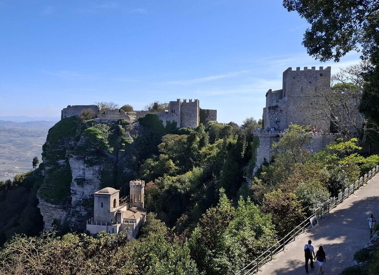 A historic castle perched atop a cliff, surrounded by lush greenery. 2