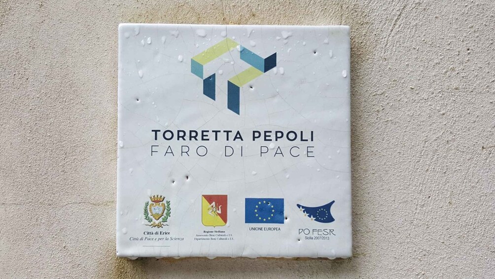 A ceramic plaque with the inscription 'TORRETTA PEOPLI FARO DI PACE' and various emblems. 5
