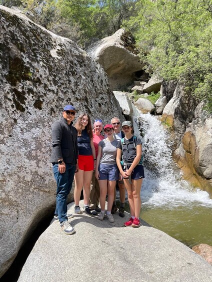 A group of people standing on a rock by a waterfall in a rocky landscape. 3