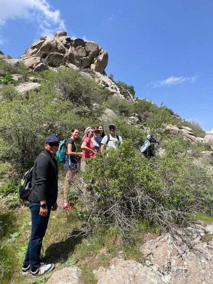 A group of hikers on a rocky hillside with sparse vegetation and a clear blue sky. 5