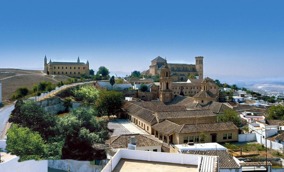 A historic town with a prominent church, a large fortress, and surrounding greenery. 1